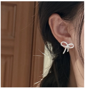 Detailed close-up of bow-shaped S925 silver earrings with sparkling zircon crystals