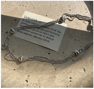Macro detail of triple-layer S925 silver beaded necklace with brushed metallic spheres