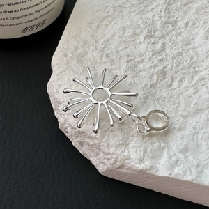 S925 Sterling Silver sunburst pendant with hollow center on stone background
