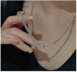 Macro shot of silver triple-layered beaded necklace with spherical accents on neck