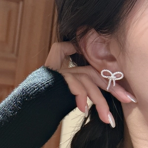 Minimalist S925 sterling silver bow earrings with twist texture on model's ear