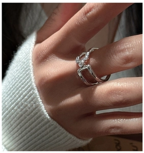Macro detail of silver geometric double-layer hollow ring with clear gemstone on hand