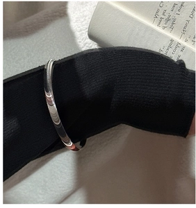 Poliertes silbernes Armband über schwarzem Ärmel für einen minimalistischen Mode-Look