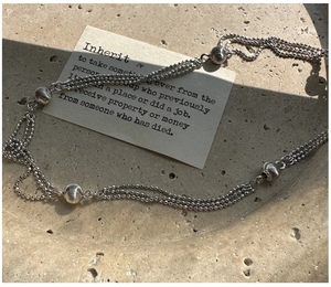 Close-up of a S925 sterling silver three-strand beaded necklace with brushed metal spheres
