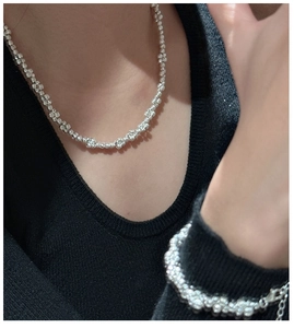 Close-up of S925 sterling silver beaded bracelet and necklace set on black knitwear