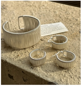 Detailed view of handmade S925 sterling silver wire-wrapped cuff bracelet and earrings