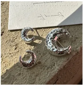 Detail view of silver S925 sterling silver crescent earrings and brooch with hammer texture