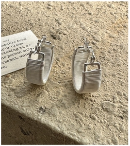 Detailed macro view of silver C-shape earrings with vintage textured wire wrap design