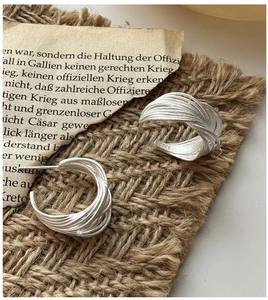 Macro detail of S925 sterling silver stamp on multi-layer wire wrapped C-shape earrings