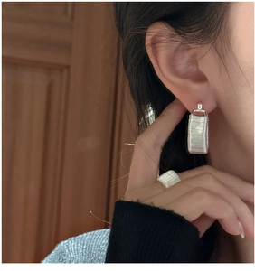 Close-up of S925 sterling silver wire-wrapped earrings and ring set on model
