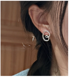 Close-up of polished S925 sterling silver twist knot earrings worn on an ear lobe