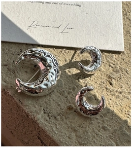 Detailed view of silver hammered moon brooch and earring set on minimalist stone