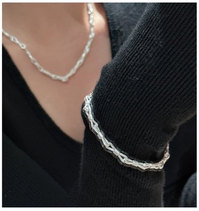 Dettaglio di collana e bracciale a maglie annodate in argento S925 su maglia nera