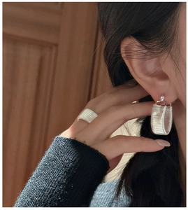 Detail of silver S925 earrings and ring featuring elegant horizontal wrapped texture design