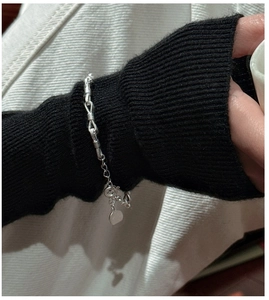Dettaglio ravvicinato di un bracciale a catena in argento S925 con nodi su manica nera