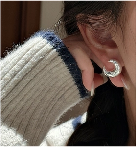 Close-up of S925 sterling silver earrings with irregular hammered texture on model