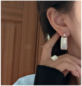 Detailed macro shot of S925 sterling silver wire-wrapped earrings and ring on model