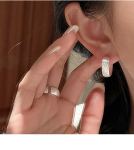 Macro detail of S925 silver brushed earrings and ring set with heart pattern