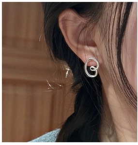 Macro detail of silver twisted knot stud earring with polished streamline design