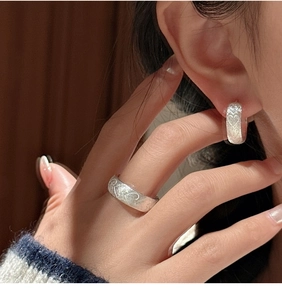 Macro detail of S925 sterling silver ring and earring set with brushed heart patterns