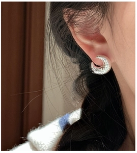 Close-up of S925 silver C-shaped earrings featuring a vintage hammered texture on model