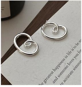 Macro shot of silver streamlined spiral earrings on vintage paper and wood