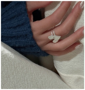 Detail of S925 sterling silver heart ring with a unique hammered texture on model's hand