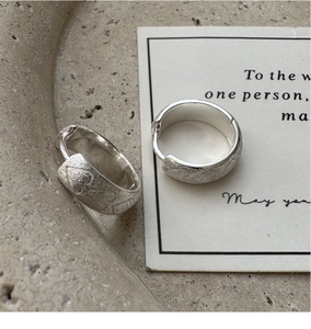 Close-up of S925 sterling silver hoop earrings with brushed texture and heart pattern