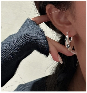 Close-up of polished S925 silver hollow teardrop earrings worn by a model