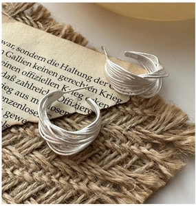 Macro detail of S925 sterling silver C-shaped earrings with unique woven wire texture