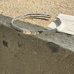 Minimalistischer S925 Sterlingsilber Armreif poliert auf Naturstein Hintergrund im Freien