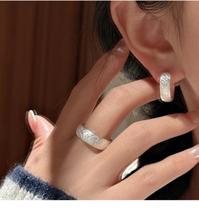 Detail of s925 silver earring and ring set featuring a matte brushed finish and heart motifs