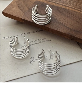 Macro shot of S925 sterling silver multi-layer line earrings on a textured wooden base
