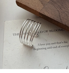 Detailed view of S925 sterling silver multi-layer wire ring on artistic paper background
