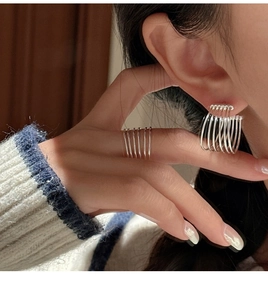 Detail shot of a layered silver earring set in a minimalist multi-strand design on model