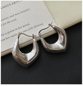 Detailed view of silver hollow shield earrings with polished mirror finish surface