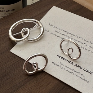 Set of three abstract oval spiral silver earrings on dark wood base and paper card