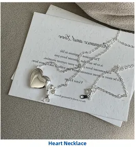 Vue détaillée du pendentif cœur argenté avec figurine d'ange sur collier fin