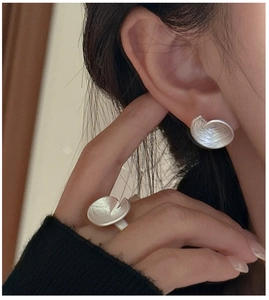 Detail shot of matte silver ring and stud earring with brushed texture and leaf design