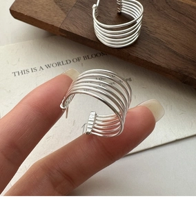 Macro view of minimalist S925 sterling silver multilayer hoop earrings with parallel lines