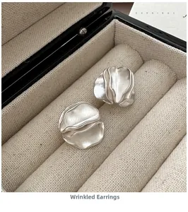 Macro shot of silver pleated earrings with organic matte finish in a jewelry box