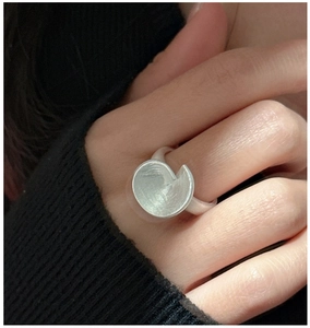 Close-up of matte silver ring with brushed texture and irregular folded disc design