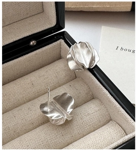 Macro detail of silver S925 earrings with a minimalist matte folded petal design
