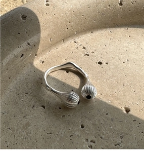 Détail macro d'une bague argentée texturée avec un point noir sur son extrémité bulbeuse