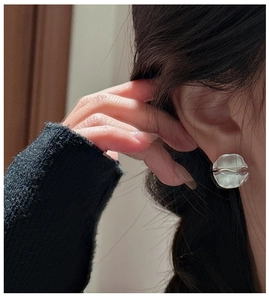 Close-up of minimalist S925 sterling silver stud earrings with textured matte finish