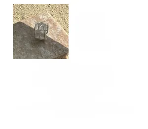 Detailed view of hollow grid texture on silver ring placed on a natural stone surface