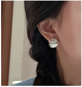 Close-up of S925 sterling silver earrings with irregular matte wrinkled texture on model