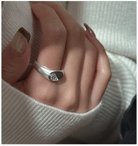 Detailed view of an S925 sterling silver ring with matte texture on white knit fabric