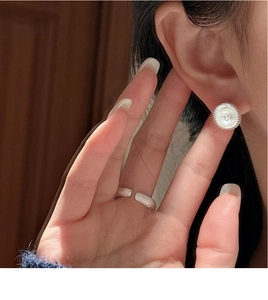Detail of S925 sterling silver hoop earring and textured open ring on female model