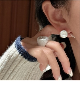 Close-up of pleated S925 sterling silver earrings and matching ring on a model